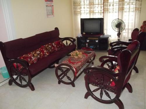 ein Wohnzimmer mit einem Sofa, Stühlen und einem TV in der Unterkunft Anura Home Stay in Kalutara