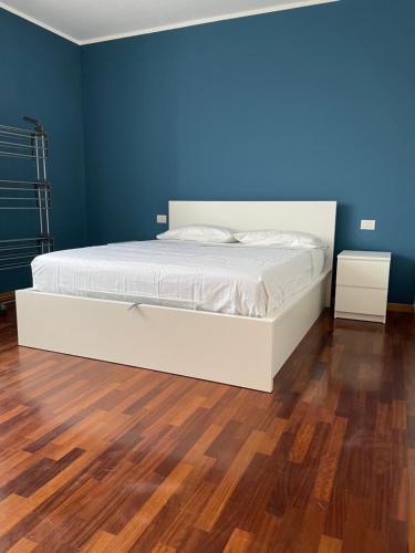 Cama blanca en habitación azul con suelo de madera en BICOCCA APARTMENT, en Milán