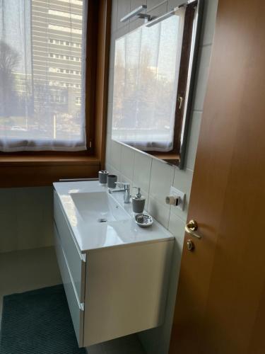 baño con lavabo blanco y ventana en BICOCCA APARTMENT, en Milán