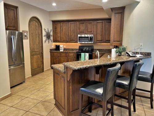 a kitchen with wooden cabinets and a kitchen island with bar stools at Bella Sirena 601-D in Puerto Peñasco