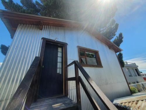 a house with a blue door and a wooden staircase at Trastienda Guest House in El Calafate