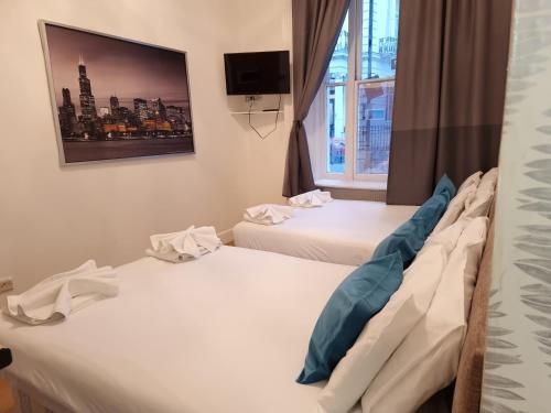 2 camas en una habitación de hotel con una foto en la pared en F6-Comfy Ground Flr Studio Fits 4- Near Paddington, en Londres