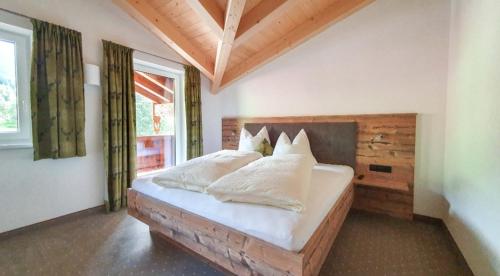 een slaapkamer met een bed met witte lakens en kussens bij Schönachhof in Gerlos