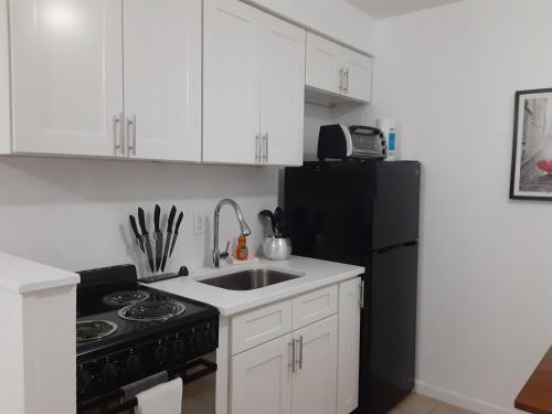 a kitchen with a sink and a black refrigerator at Singer Island Inn in West Palm Beach