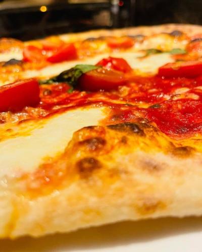 a close up of a pizza with tomatoes and cheese at Hotel Fiescherhof in Fiesch