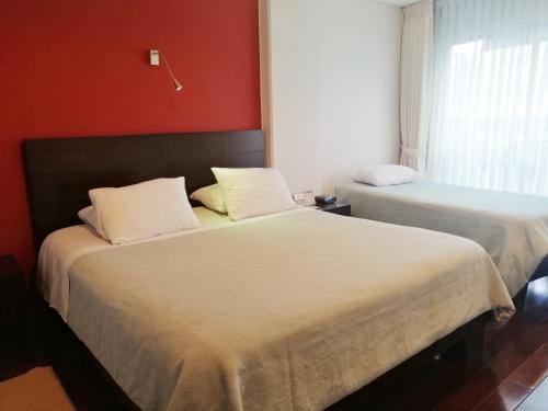 ボゴタにあるApartasuites BellHouse Bogotáの赤い壁の部屋にベッドが2つある