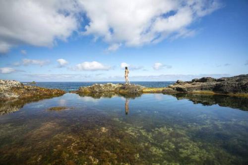 a person standing on a small island in the water at Casa Azul: A magic place in an authentic space in Mosteiros