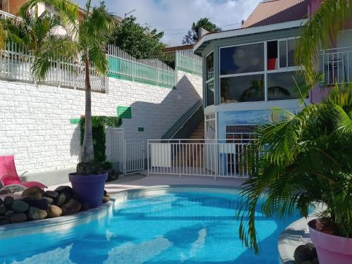 a pool in front of a house with a palm tree at Appartement charmant à Sainte-Anne avec piscine partagée - 60 m² in Sainte-Anne