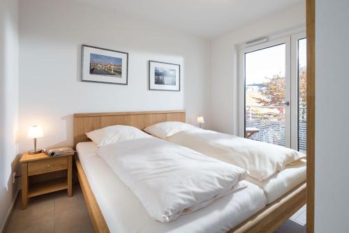 1 dormitorio con 2 camas con sábanas blancas y ventana en Schippershuus 10, en Norderney