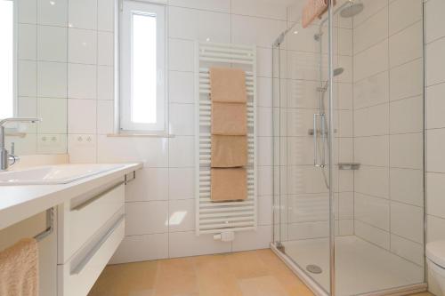 un bagno bianco con doccia e lavandino di Penthaus 15 Strandvilla Therese a Norderney