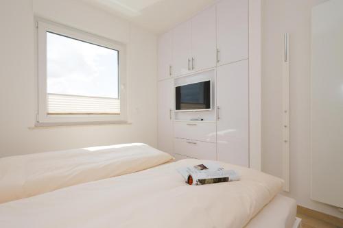 una camera da letto bianca con due letti e una TV di Penthaus 15 Strandvilla Therese a Norderney