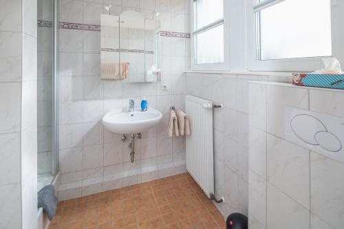 a white bathroom with a sink and a window at Rubintje Nord in Norderney