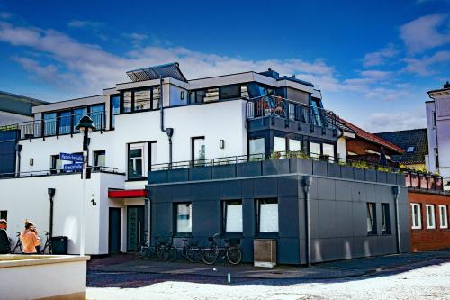 - un grand bâtiment blanc avec des vélos sur le balcon dans l'établissement Seebox Appartment 3, à Norderney