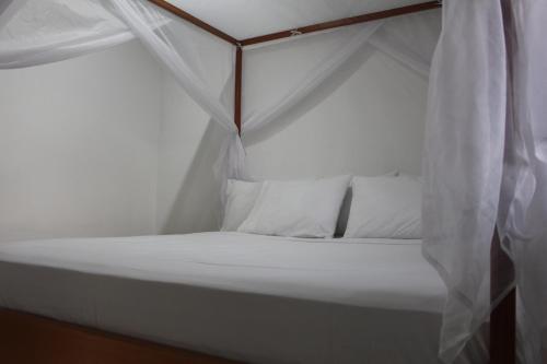 a white bed with white pillows and a canopy at Serranía Eco Lodge in San Juan de Arama