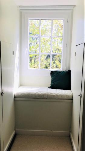 a window seat in front of a window with a green pillow at Manoir du Bois Mignon in Le Fleix