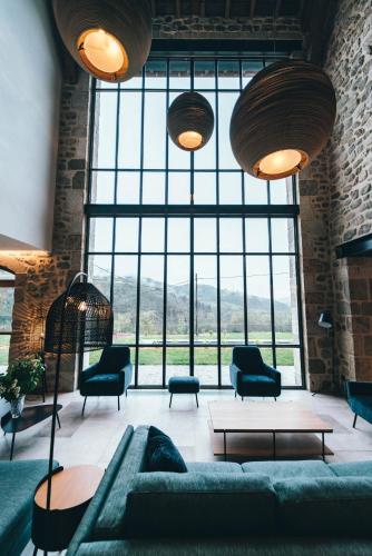 a living room with a couch and chairs and a large window at La ferme d'Edouard - Les Fermes Ardéchoises in Labatie-dʼAndaure