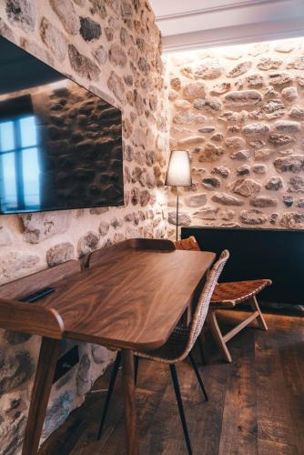 a wooden table in a room with a stone wall at La ferme d'Edouard - Les Fermes Ardéchoises in Labatie-dʼAndaure