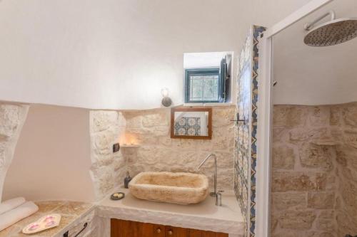 een badkamer met een stenen douche en een wastafel bij Trullo DONNA LUCIA in Latiano