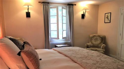 a bedroom with a bed and a chair and a window at Manoir du Bois Mignon in Le Fleix