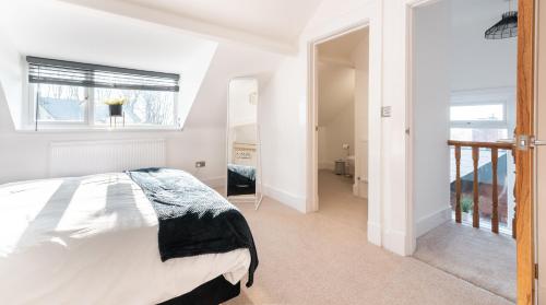 a white bedroom with a bed and a window at Tŷ Hapus Newport - Luxury 4 Bedroom Home in Newport