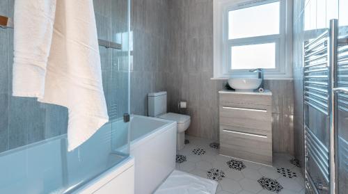 a bathroom with a tub and a toilet and a window at Tŷ Hapus Newport - Luxury 4 Bedroom Home in Newport