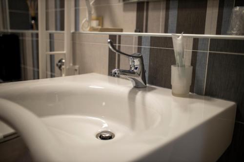 a white bathroom sink with a toothbrush in a holder at IL PALAZZO - Luxury Home & Event in Cosenza