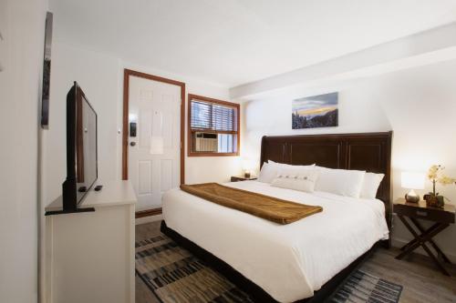 um quarto com uma grande cama branca e uma televisão em Attractive Townhouse in Whistler Village with Hot Tub em Whistler