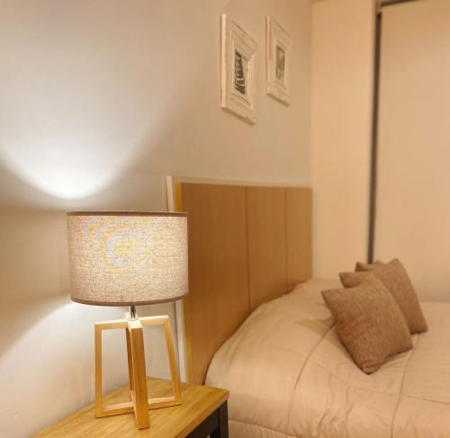 a lamp sitting on a table next to a bed at Sucre Suites in Buenos Aires