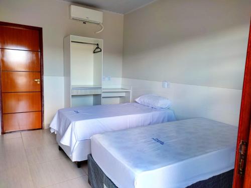 una habitación de hotel con 2 camas y una puerta en Pousada Portal da Villa, en Vitória da Conquista