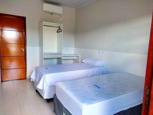 a hotel room with two beds and a door at Pousada Portal da Villa in Vitória da Conquista
