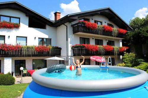 una mujer en una piscina frente a una casa en Garden Apartments Janša, en Radovljica