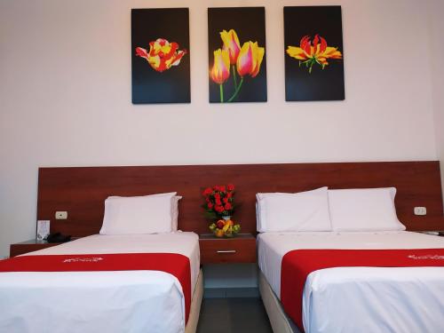 two beds in a hotel room with flowers on the wall at HOTEL SAN JUAN, Tarapoto in Tarapoto