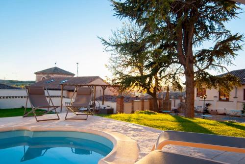 a swimming pool with two chairs and a tree at Hotel Rural El Cedro in Lerma