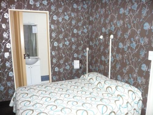 a bedroom with a bed with a floral wallpaper at Hôtel - Restaurant Saint Jacques in Blois