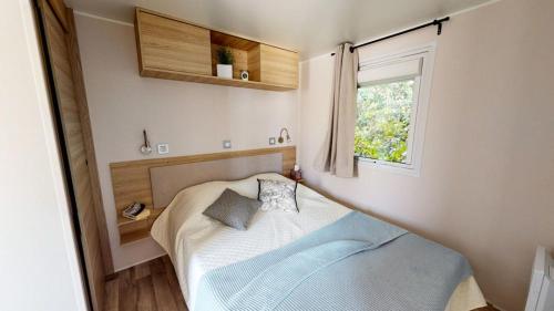 a small bedroom with a bed and a window at NEW Jungle Lake - Clim - WIFI - Draps & serviettes - BBQ - 10' des plages in Lattes