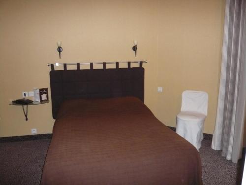 a bedroom with a large bed and a white chair at Hôtel - Restaurant Saint Jacques in Blois