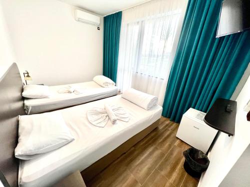 - 2 lits dans une chambre d'hôtel dotée de rideaux bleus dans l'établissement Paradise Park, à Polski Trŭmbesh