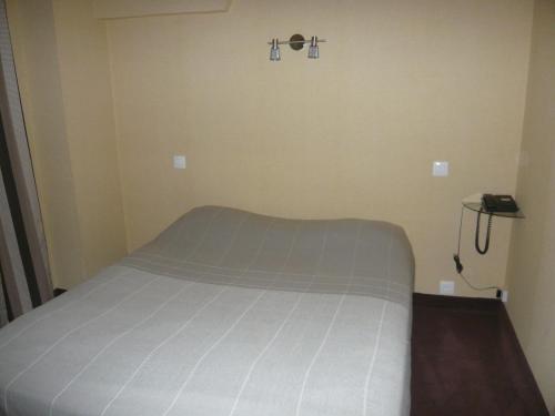 a bed in a small room with two crosses on the wall at Hôtel - Restaurant Saint Jacques in Blois