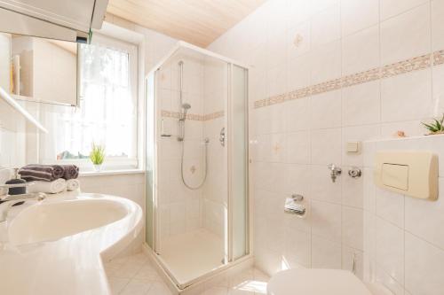 ein weißes Bad mit einer Dusche und einem Waschbecken in der Unterkunft Ferienwohnungen Gewiese in Schierke