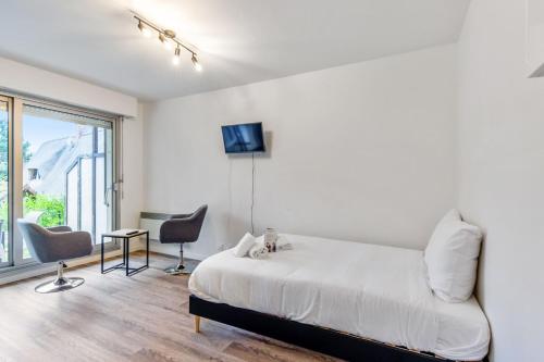 une chambre blanche avec un lit, une table et des chaises dans l'établissement Studio Aristide - Welkeys, à Cabourg