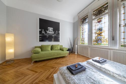 a living room with a green couch and stained glass windows at Elisabeth Apartment on Váci Street in Budapest