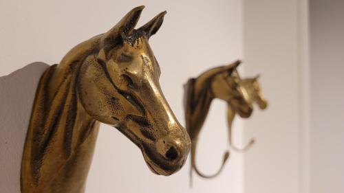 a gold horse head on a wall next to another horse mask at Hoeve Spyckergoed in De Haan