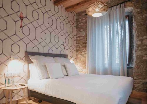 a bedroom with a white bed and a stone wall at Les Quingles in Calders