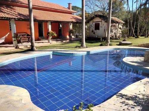 uma piscina com azulejos azuis em frente a uma casa em Pousada & Restaurante Chico Bento em Lambari