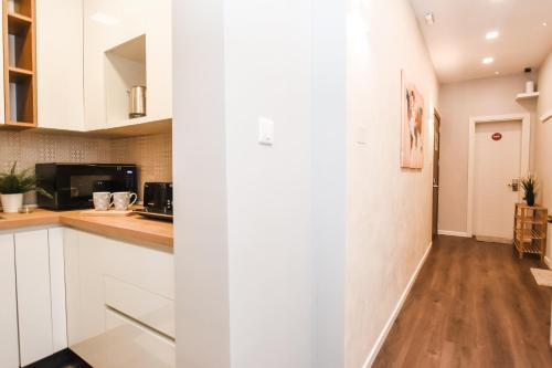 a kitchen with white cabinets and a wooden floor at Cosy Albert's Seaside Suites (Sliema) in Sliema