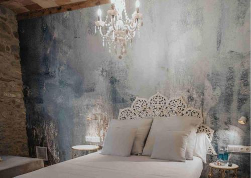 a bedroom with a white bed and a chandelier at Les Quingles in Calders