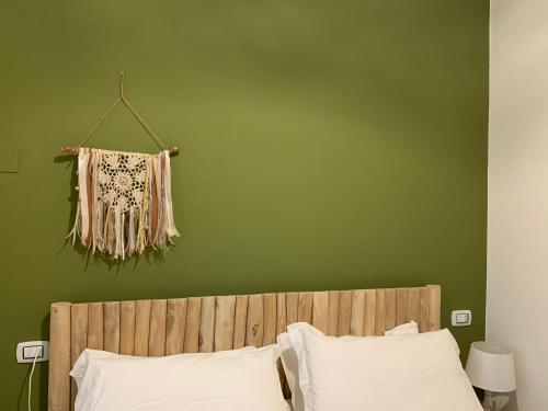 Un dormitorio con una pared verde y una cama con almohadas blancas. en AGRIB&B Il Pomo d'oro, en Assemini