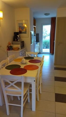 cocina y comedor con mesa y sillas en Maison duplex 2 chambres, avec jardin, 800m plage, en Belgodère