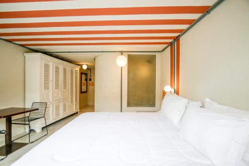 Habitación con una gran cama blanca y una mesa. en Selina Buzios, en Búzios
