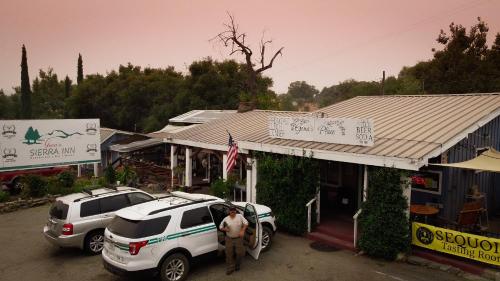 a man standing in front of a building with a car at Genas's Sierra Inn & Restaurant in Dunlap